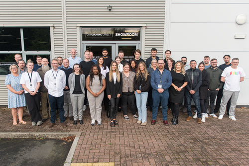 A large group of the UK Flooring Direct staff stood across the door of the Coventry showroom looking towards the camera